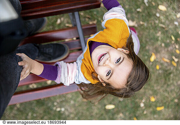 Smiling girl looking up standing on bench