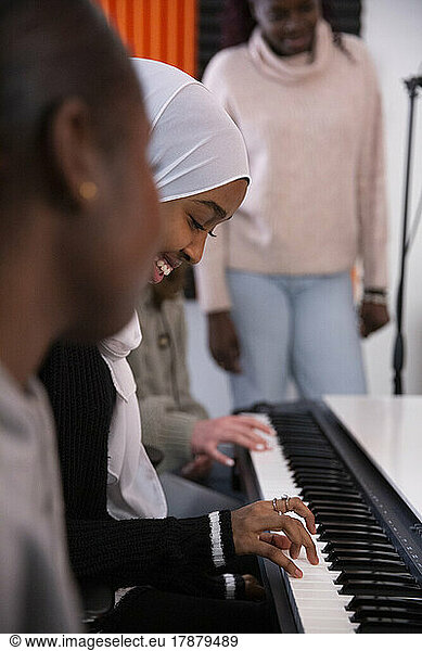 Smiling girl playing piano in recording studio