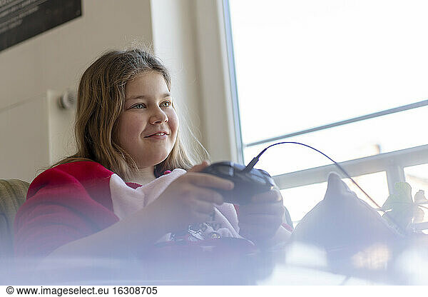 Smiling girl playing video game at home