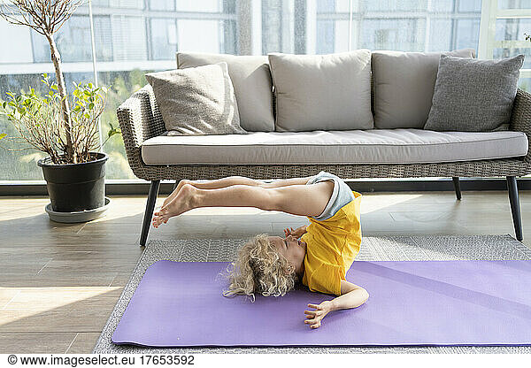 Smiling girl practicing yoga in front of sofa at home