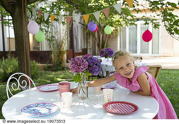Smiling girl setting table for birthday event in garden
