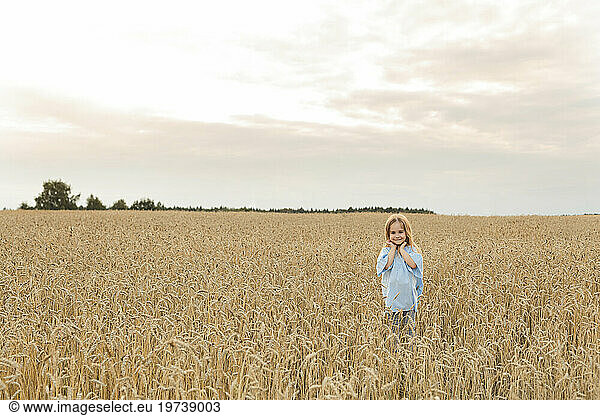 Smiling girl standing amidst field under sky