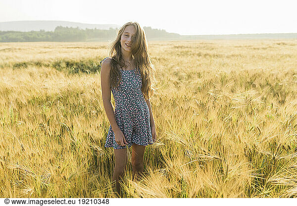 Smiling girl standing amidst wheat crop in field