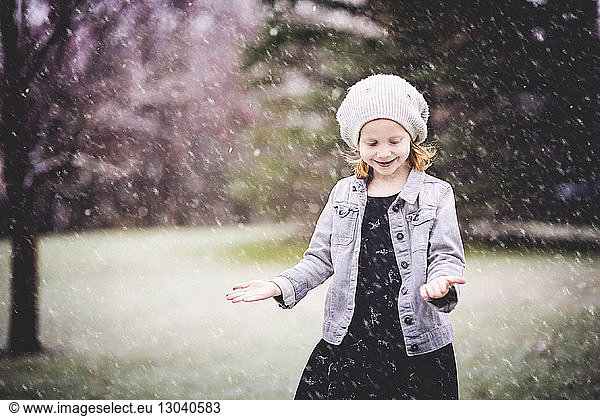 Smiling girl standing at park during snowfall