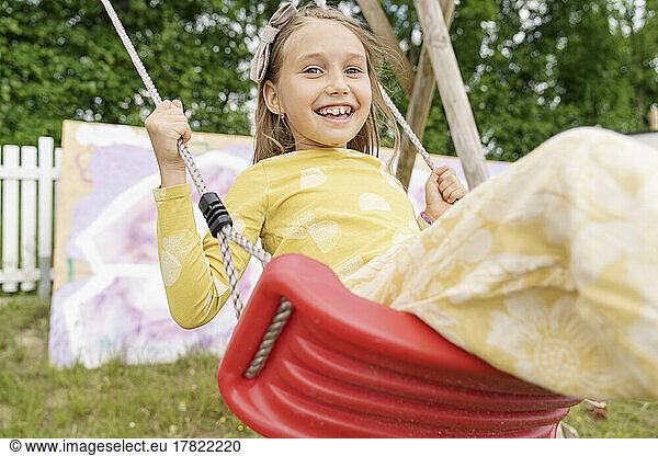Smiling girl swinging on swing at playground