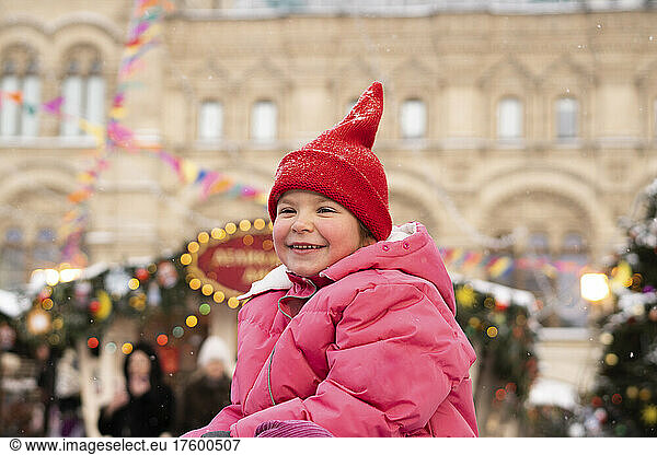 Smiling girl wearing knit hat at Christmas market