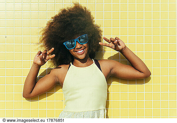 Smiling girl wearing sunglasses gesturing peace sign
