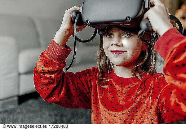 Smiling girl wearing virtual reality simulator at home