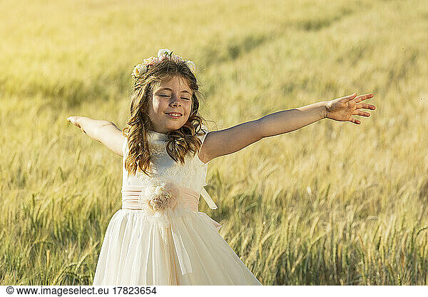 Smiling girl with arms outstretched in meadow