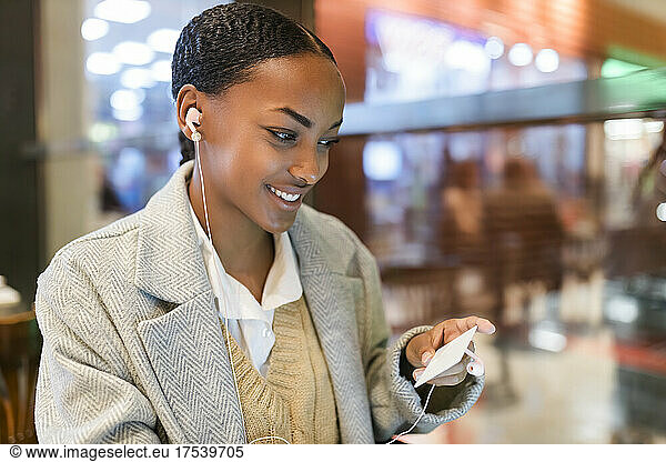 Smiling girl with earphones holding credit card