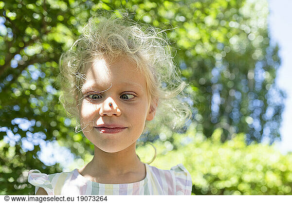 Smiling girl with ladybug on nose in park