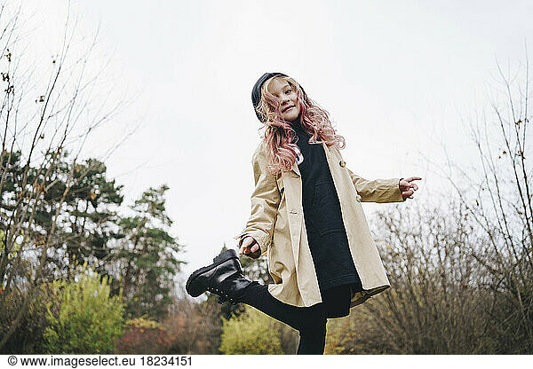 Smiling girl with pink hair standing in park under sky