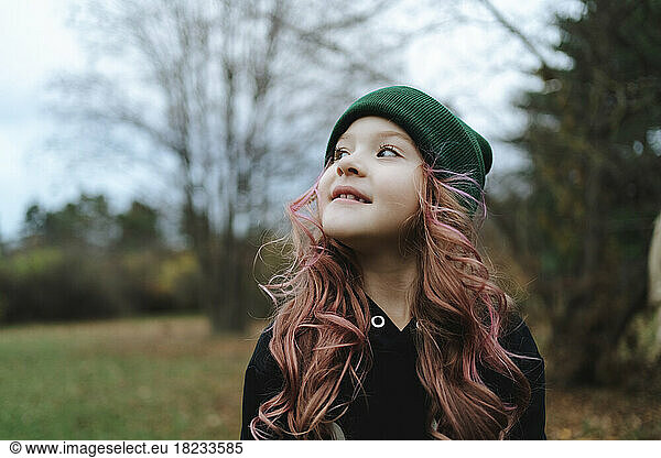 Smiling girl with pink hair wearing knit hat in park
