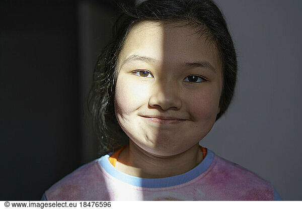 Smiling girl with sunlight on face at home