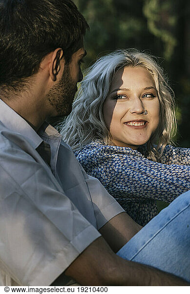 Smiling girlfriend staring at boyfriend on sunny day