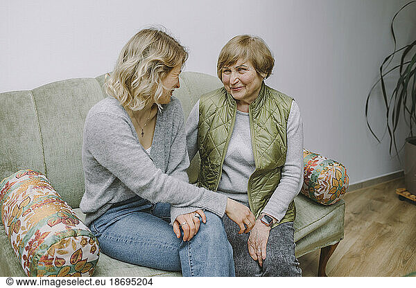 Smiling grandmother sitting with granddaughter on sofa