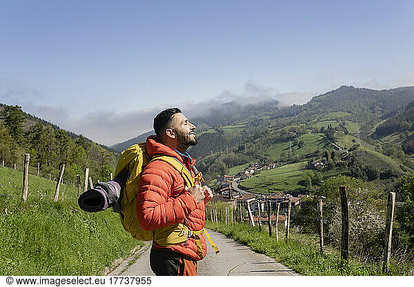 Smiling hiker wearing backpack enjoying sunny day