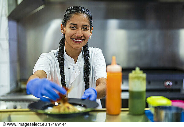 Smiling kitchen trainee food styling in restaurant