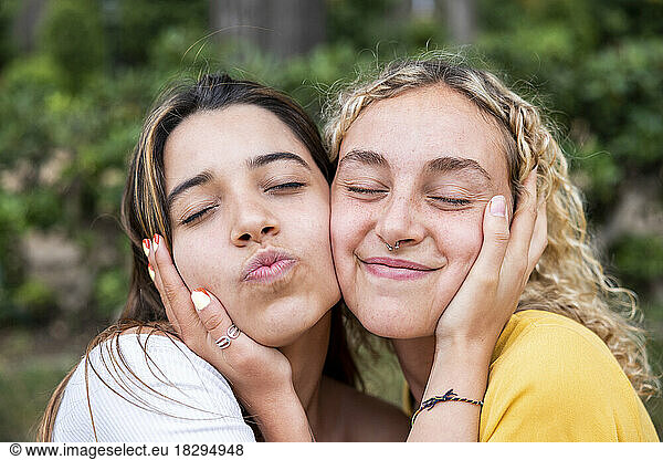 Smiling lesbian couple with cheek to cheek in park
