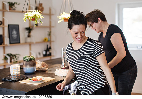 Smiling lesbian couple working in kitchen at home