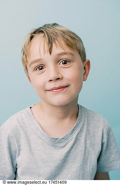 Smiling little boy on baby blue background