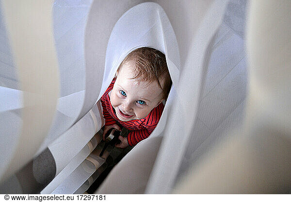 smiling little girl hiding in curtains