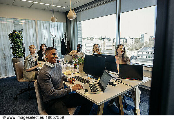 Smiling male and female business colleagues during video conference in coworking office