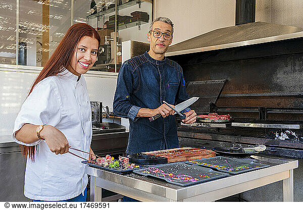 Smiling male and female chefs working in kitchen