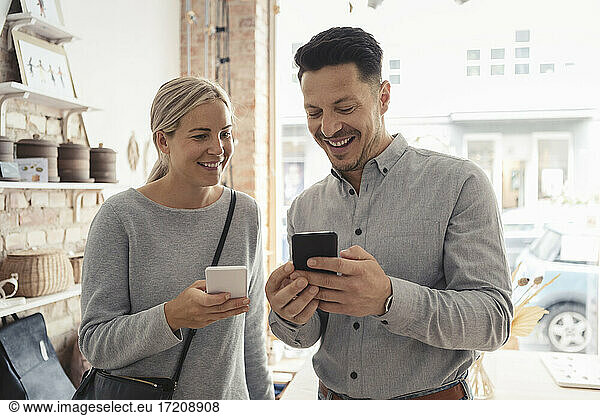 Smiling male and female customers using smart phone in design studio