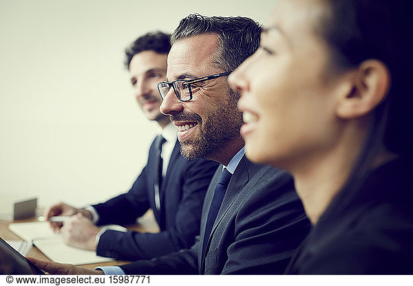 Smiling male and female financial colleagues sitting in office during meeting