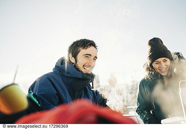 Smiling male and female friends enjoying at ski resort