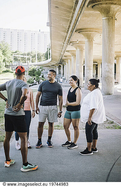 Smiling male and female multiracial friends talking to each other after work out