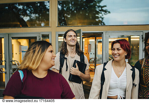 Smiling male and female student talking with each other in university campus