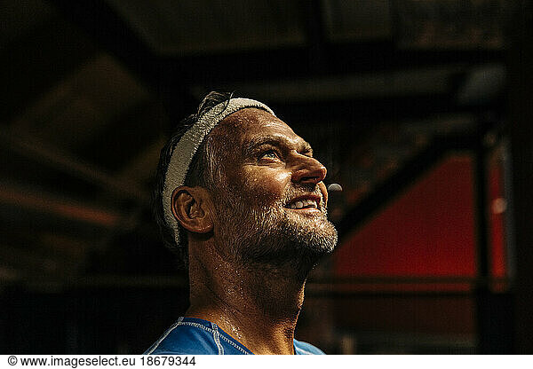 Smiling male athlete wearing headband while contemplating at sports court