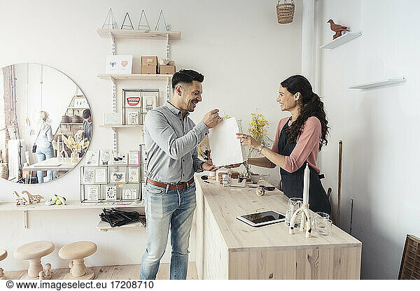 Smiling male customer taking packaged product from female owner in store