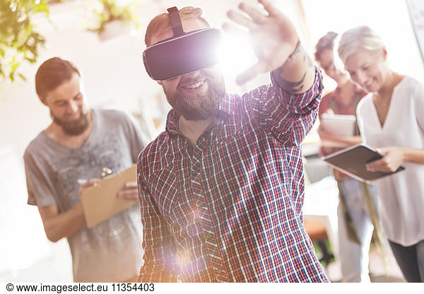 Smiling male design professional using virtual reality simulator glasses in meeting