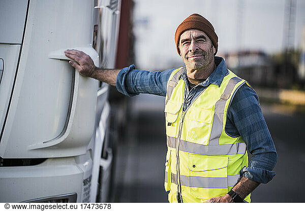 Smiling male driver standing by truck