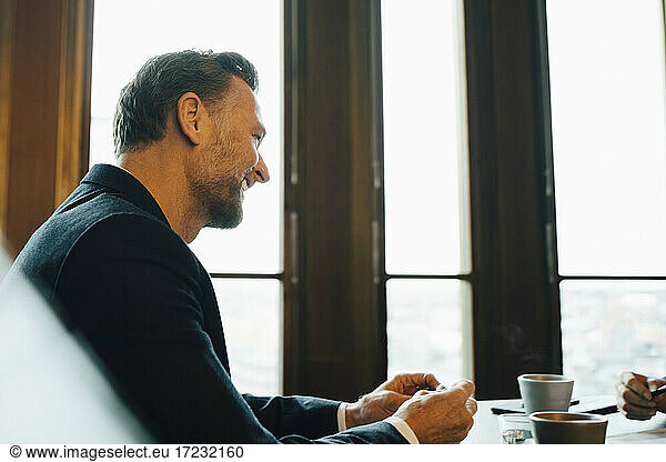 Smiling male entrepreneur in discussion with colleague in office