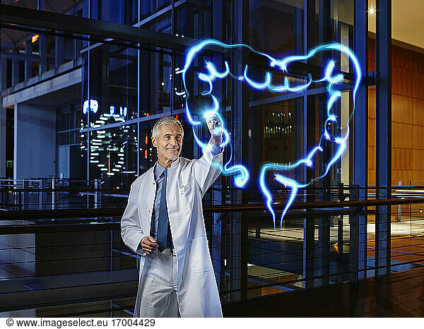 Smiling male gastroenterologist examining large intestine with light painting at hospital