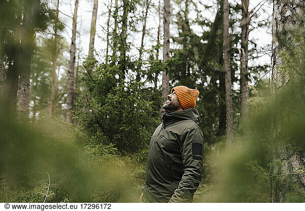 Smiling male hiker looking up while standing in forest