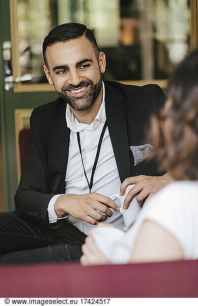 Smiling male professional looking at female colleague while discussing during networking event