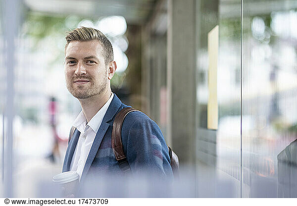 Smiling male professional standing at bus stop