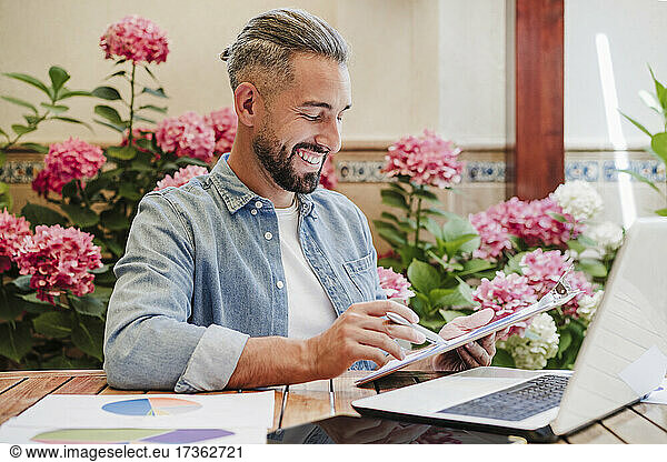 Smiling male professional working on graphs at desk