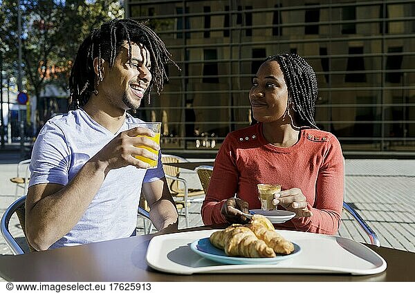 Smiling man and woman having breakfast at sidewalk cafe