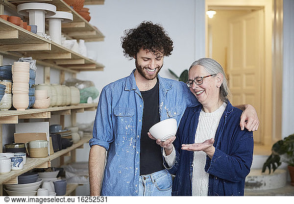 Smiling man and woman looking at bowl in pottery class