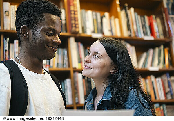 Smiling man and woman looking at each other in library
