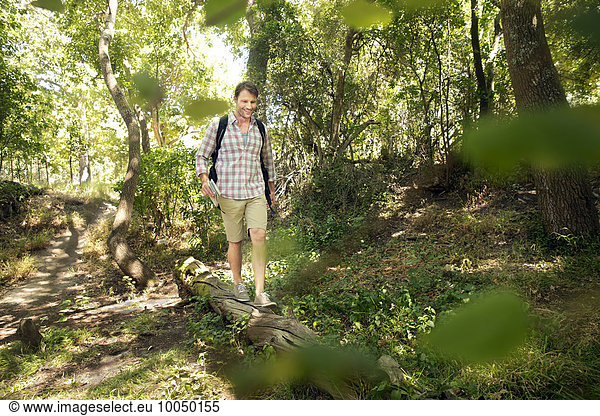 Smiling man balancing on log in forest