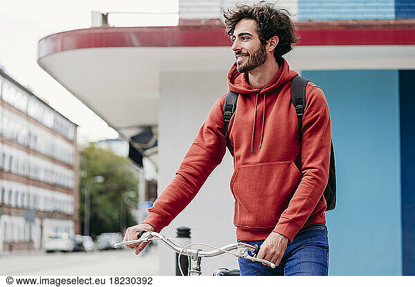Smiling man crossing road holding bicycle