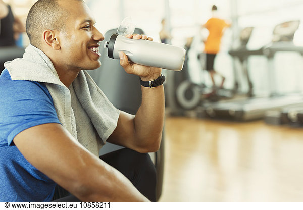 Smiling man drinking water at gym