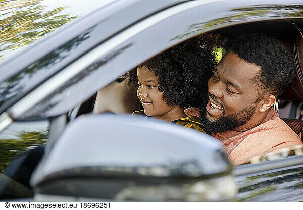Smiling man enjoying road trip with daughter in car